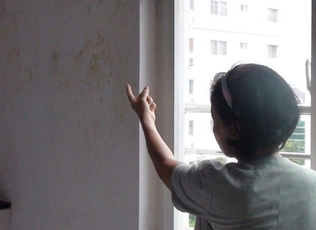 Bà K.A chỉ cho phóng viên xem khu vực tường bị nước toalet nhà tầng trên thấm ướt