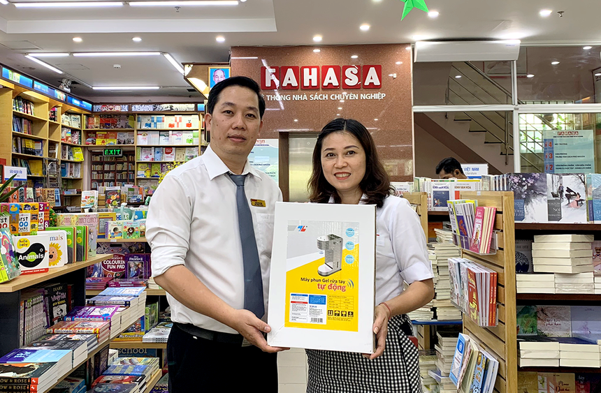 Đại diện nhà sách Fahasa Tân Bình (bên trái) nhận Máy phun gel rửa tay tự động từ đại diện công ty Thiên Long Hoàn Cầu – công ty thành viên của Kl994 game bài casino hấp dẫn Thiên Long.