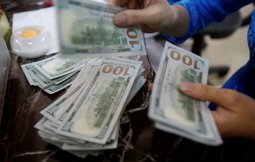 Một nhân viên Link Vào Nhà Cái KL99 COM Tặng +199k đếm tiền USD tại Hà Nội. Ảnh: Reuters.
