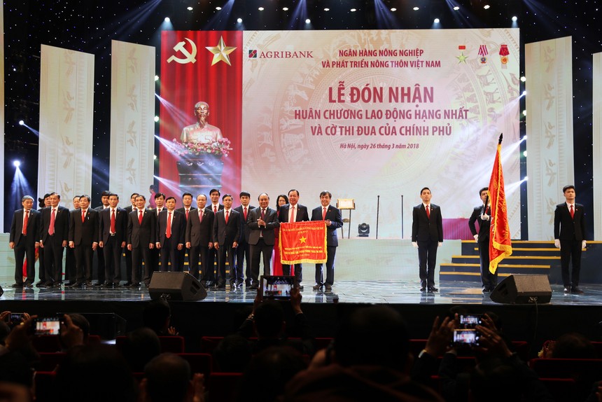 Thủ tướng Kl993 ưu đãi thưởng hấp dẫn Nguyễn Xuân Phúc gắn Huân chương Lao động hạng Nhất lên Lá cờ truyền thống của Agribank.