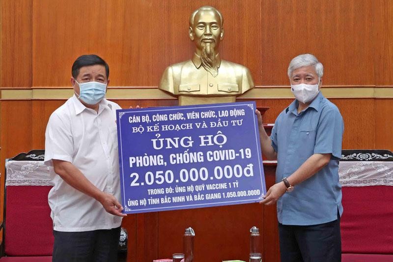 Đại diện Bộ Kế hoạch và Kl99ok phiên bản mới, Bộ trưởng Nguyễn Chí Dũng (bìa trái) trao 2,05 tỷ đồng đóng góp cho hoạt động phòng chống dịch Covid-19 cho Chủ tịch Ủy ban Trung ương MTTQ Việt Nam Đỗ Văn Chiến (Ảnh: Đức Trung)
